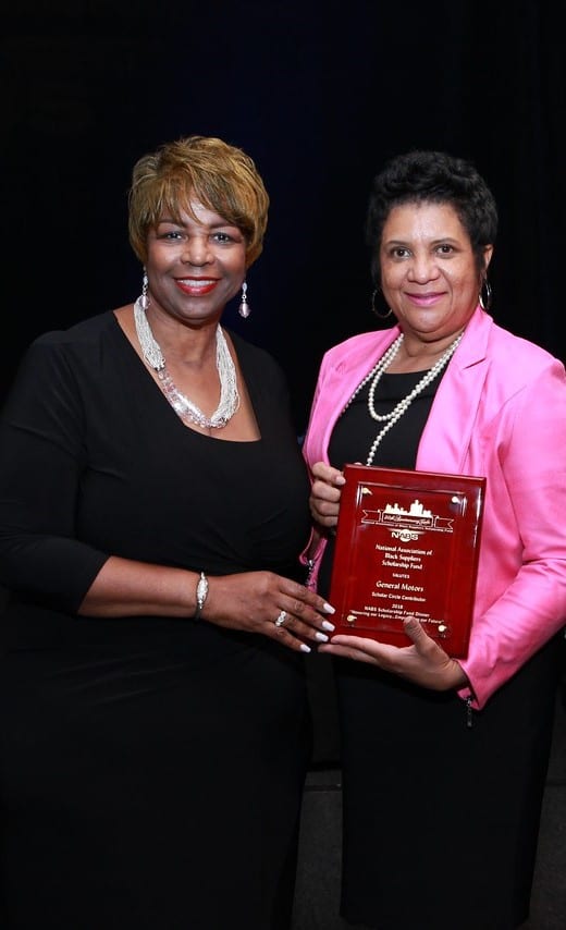 Two women holding a plaque and posing for the camera.