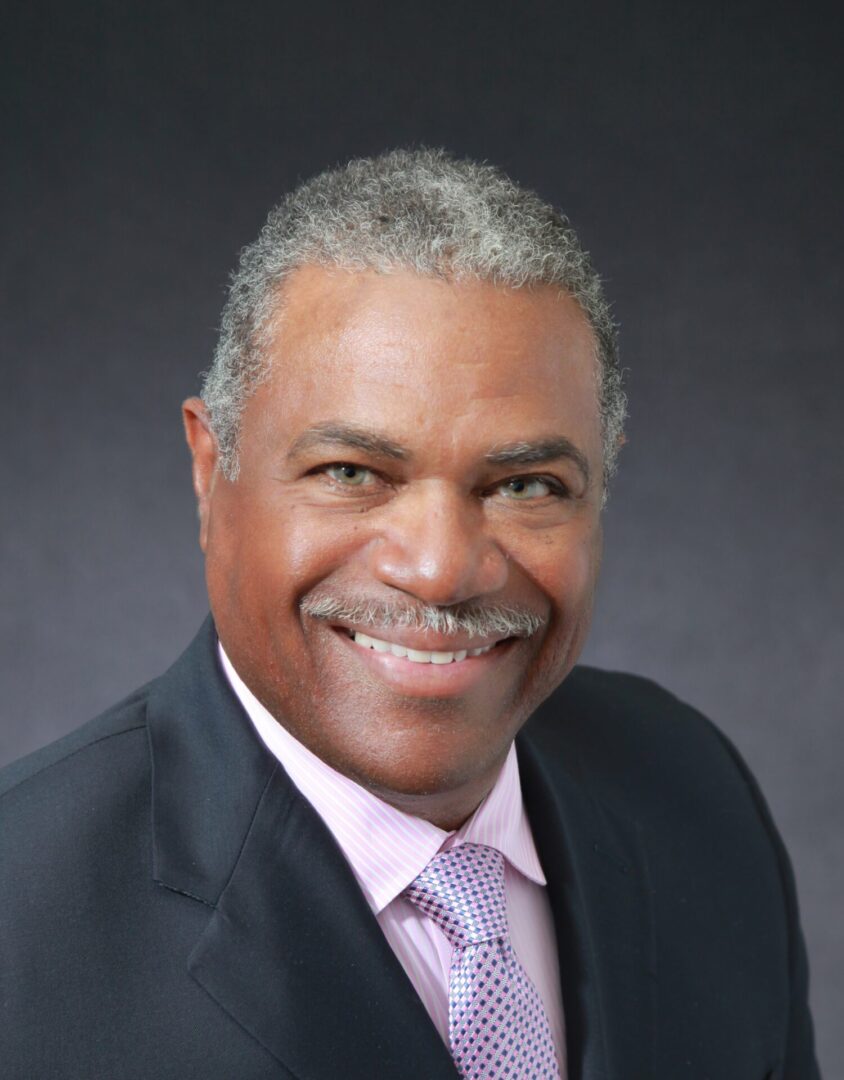 A man in a suit and tie smiling for the camera.